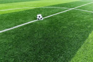Football artificial grass pitch with white field lines and a ball resting on the surface