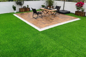 Leisure artificial grass around a wooden patio deck with outdoor table and chairs